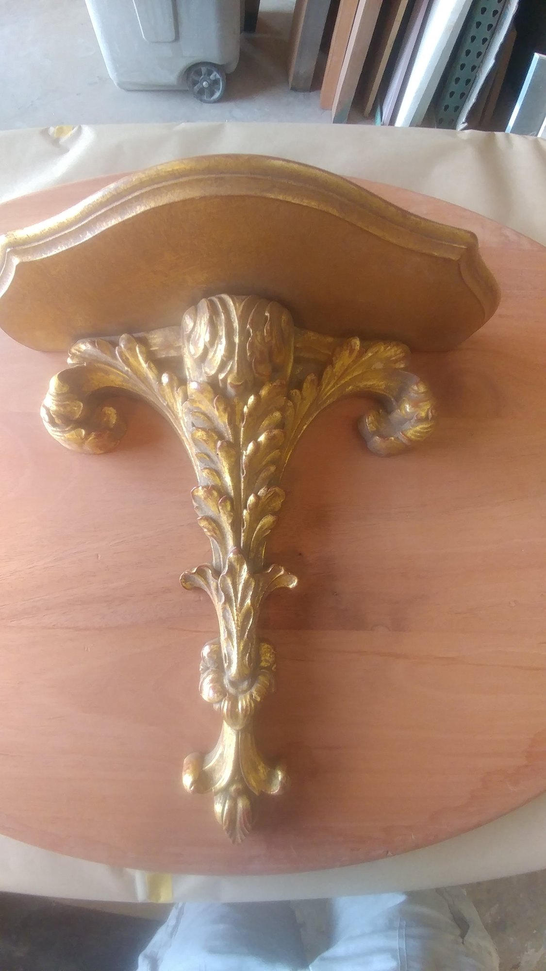 Carved wall bracket with a gilded acanthus leaf ornament against plain unfinished wood