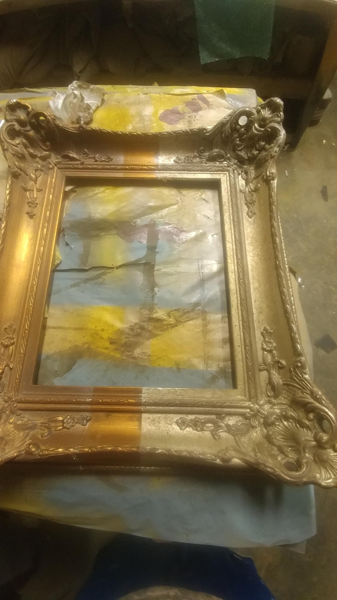 Gilded and antiqued picture frame surrounding a painting in a Dallas gilding workshop