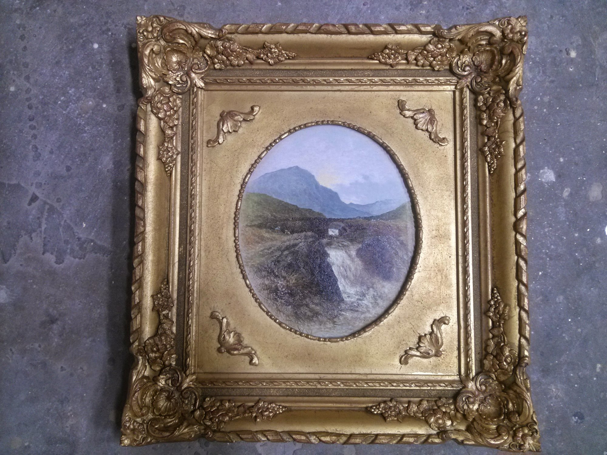 Finished gilded frame, toned and aged, around an oval-mounted landscape painting