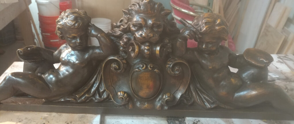 Antique gilded cherub and lion carving before restoration