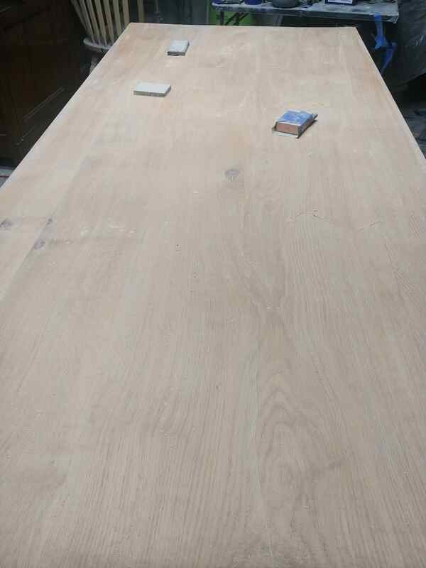 The German oak table top sanded back to bare wood, with sanding blocks resting on the surface