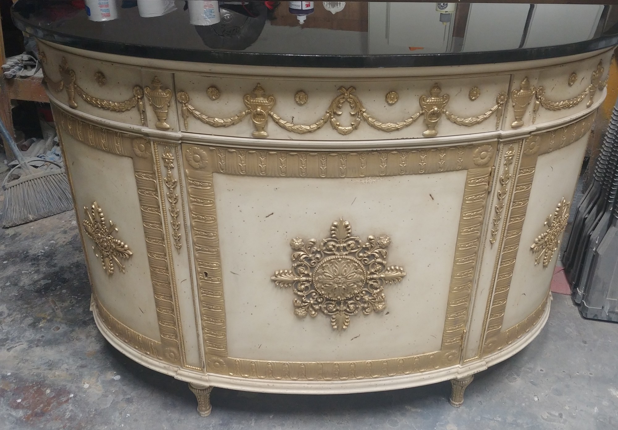 Demilune cabinet after Roman gilding, carved details finished in antiqued gold with no shine
