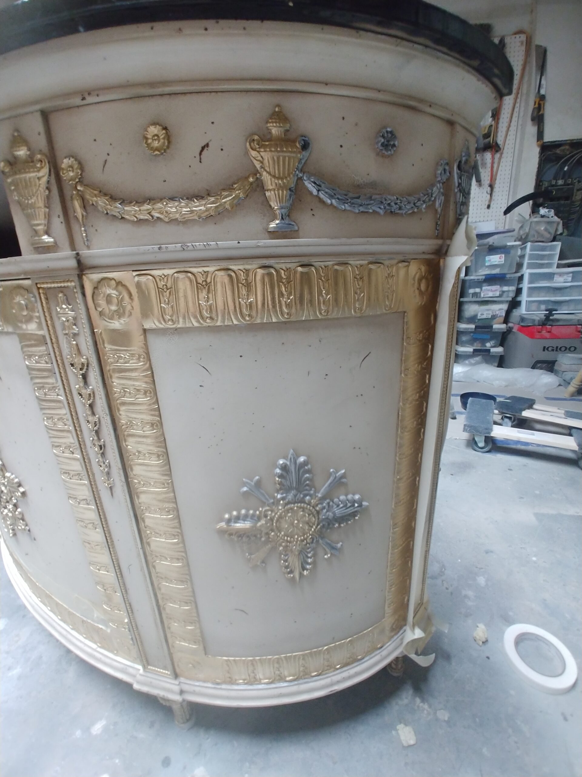 Roman gilding in process on a demilune cabinet, with gold replacing the old silver paint on the carved details